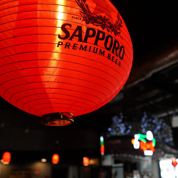 A large red Sapporo Premium Beer lantern hangs in a dimly lit Korean BBQ restaurant.